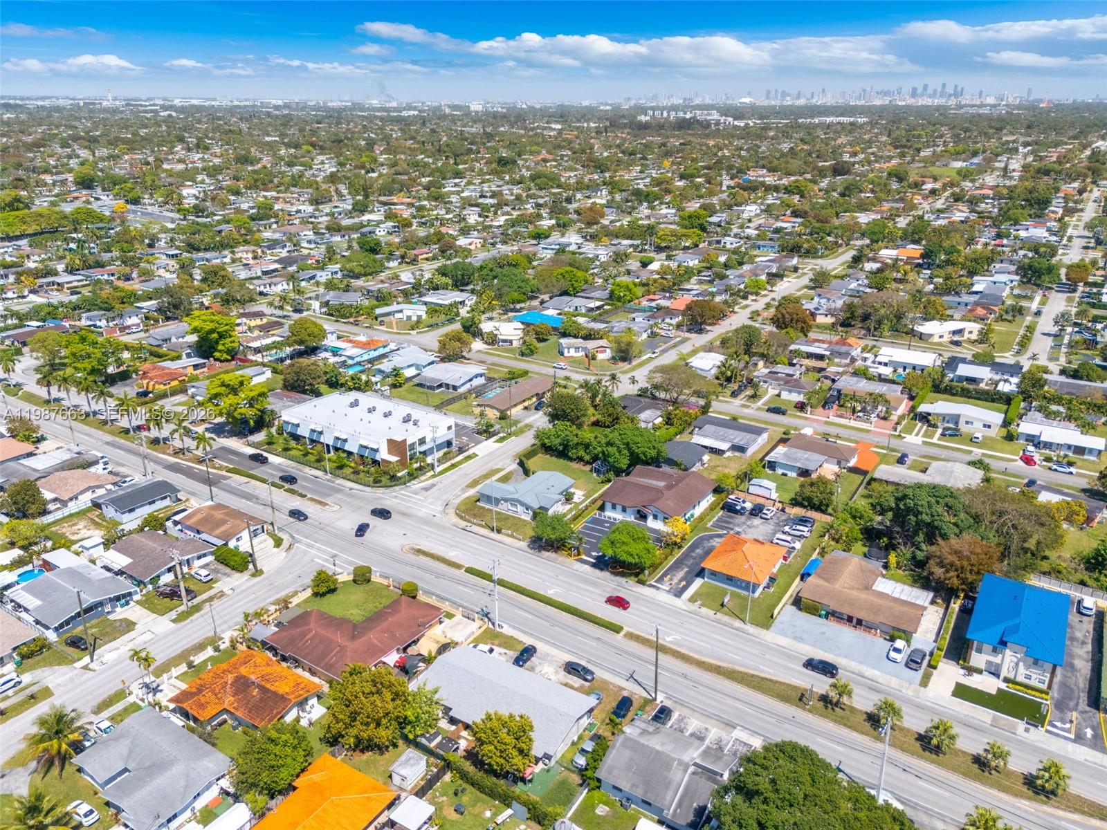 An aerial view shows a suburban neighborhood with houses, streets, and a distant city skyline — 3630 SW 87th Ave, Miami FL 33165, MIAMI, FL