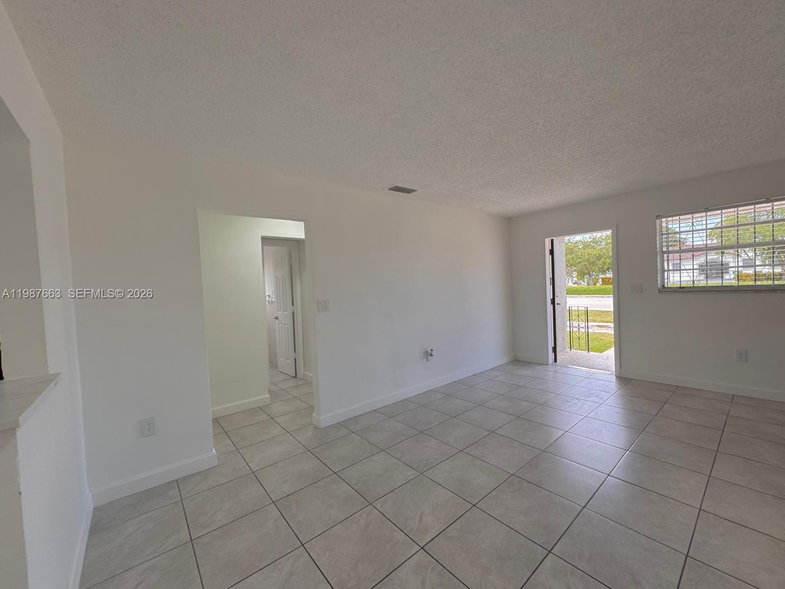 A bright room with white walls, light-colored tile flooring, and an open doorway leading outside — 3630 SW 87th Ave, Miami FL 33165, MIAMI, FL