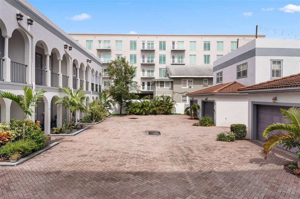 A paved courtyard sits between a multi-story apartment building and a detached garage structure — 628 3RD AVENUE S, ST PETERSBURG, FL