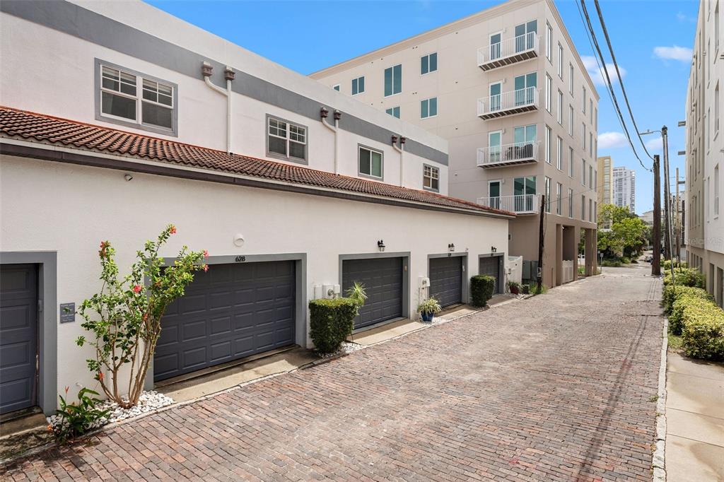 A brick alleyway leads to a row of garage doors beneath a multi-story building — 628 3RD AVENUE S, ST PETERSBURG, FL