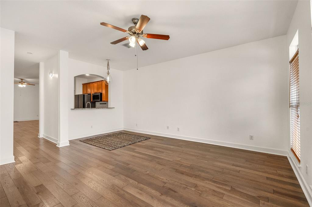 A living area with wood-look flooring, a ceiling fan, and an arched kitchen pass-through window — 628 3RD AVENUE S, ST PETERSBURG, FL
