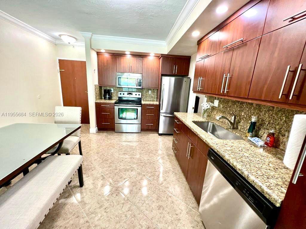 A kitchen features wood cabinets, granite countertops, stainless steel appliances, and tile flooring — 3801 S Ocean Dr # 2C, Hollywood FL 33019, HOLLYWOOD, FL