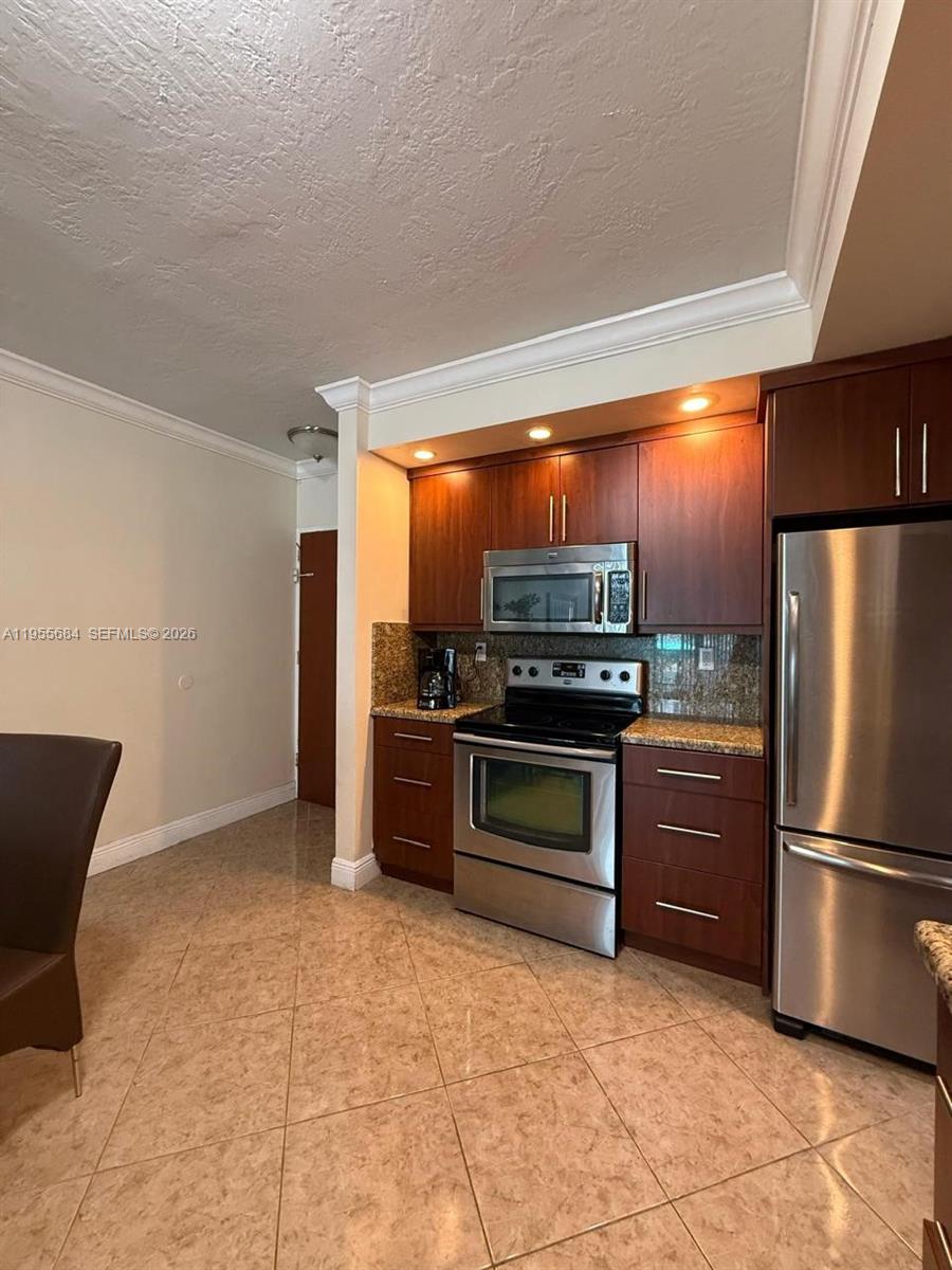 A kitchen features dark wood cabinets, stainless steel appliances, and tan tile flooring — 3801 S Ocean Dr # 2C, Hollywood FL 33019, HOLLYWOOD, FL