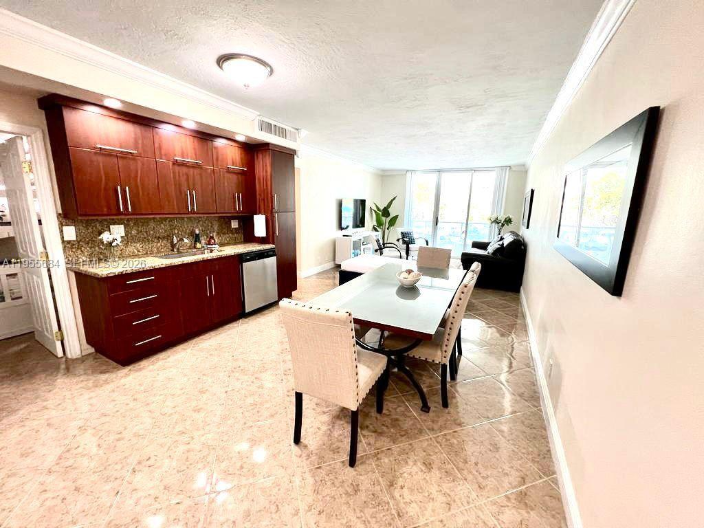 A kitchen with dark wood cabinets and a dining area with a glass table — 3801 S Ocean Dr # 2C, Hollywood FL 33019, HOLLYWOOD, FL