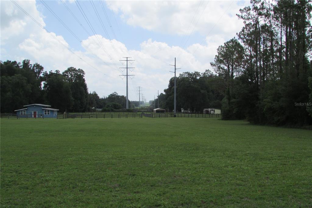 A large grassy field features a blue building and power lines under a cloudy sky — 10455 NW GAINESVILLE ROAD, OCALA, FL
