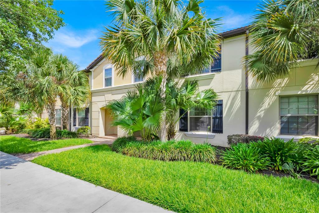 A two-story residential building with beige stucco walls, dark shutters, and surrounding palm trees — 8952 ADRIATICO LANE, KISSIMMEE, FL