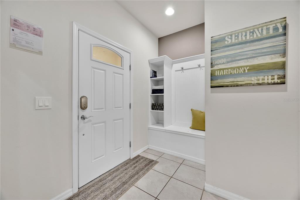 An entryway features a white front door, tiled flooring, and a built-in storage bench unit — 8952 ADRIATICO LANE, KISSIMMEE, FL