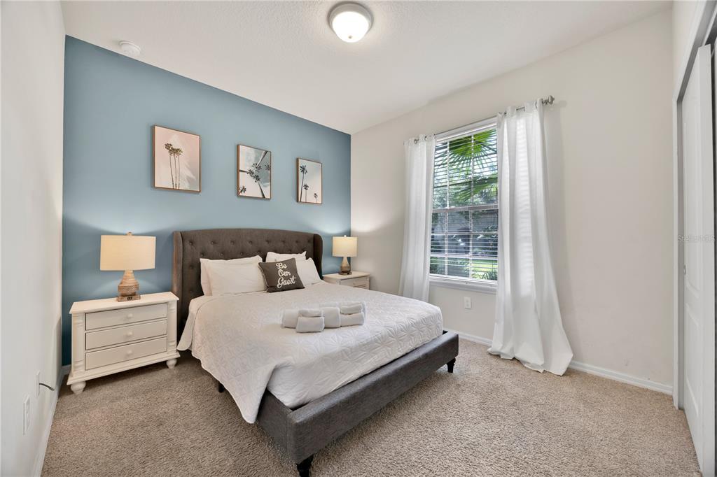 A bedroom features a blue accent wall, a gray upholstered bed, and white curtains — 8952 ADRIATICO LANE, KISSIMMEE, FL