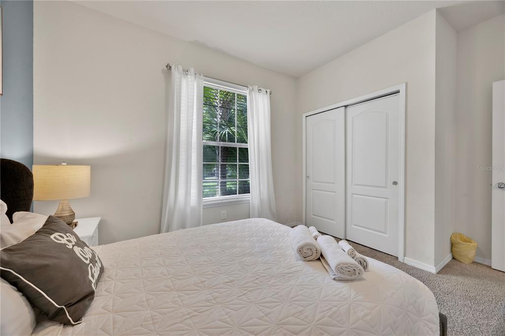 A bedroom features a bed with white bedding, a window with white curtains, and a closet — 8952 ADRIATICO LANE, KISSIMMEE, FL