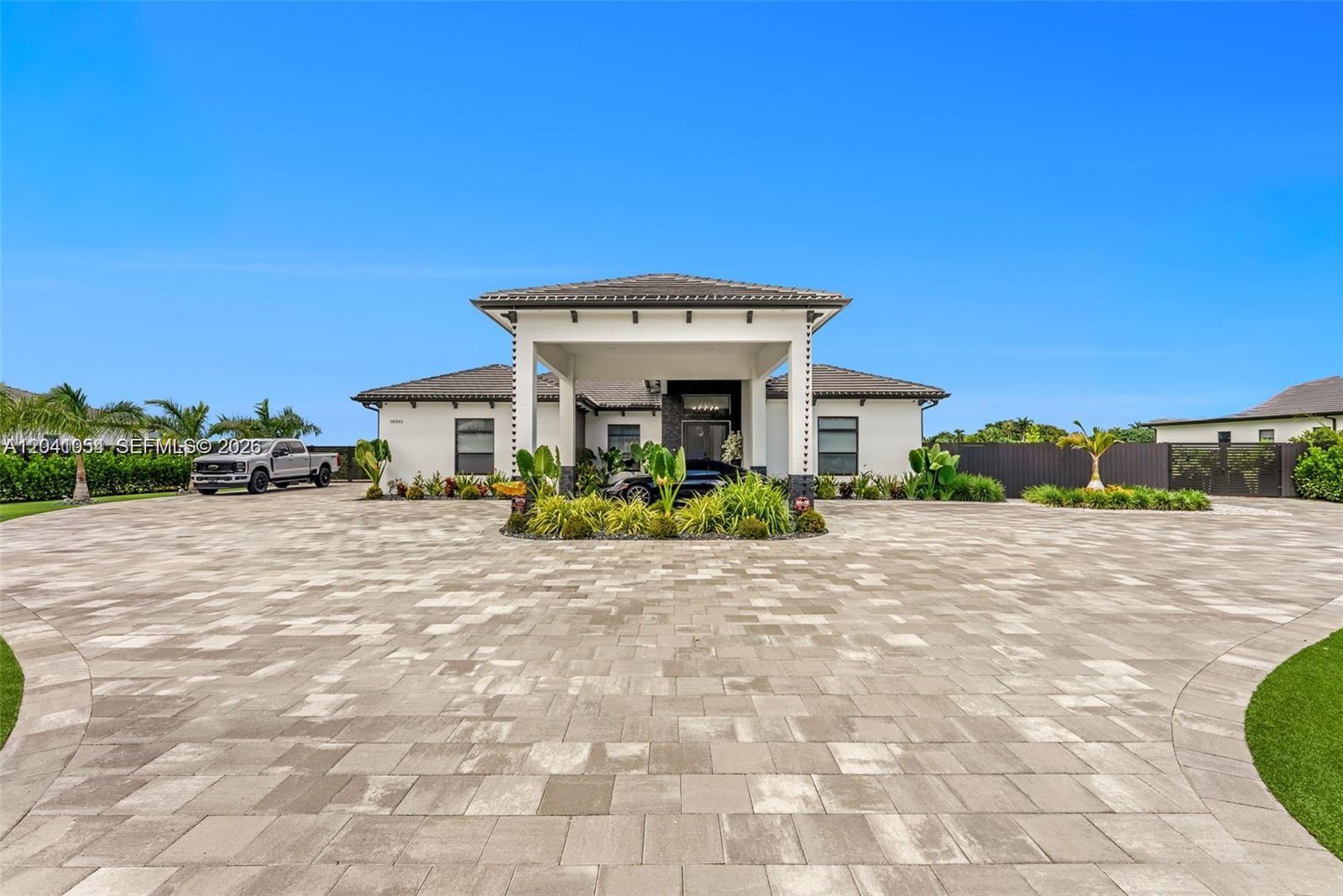 A modern single-story house features a large porte-cochère and an expansive paved driveway — 18261 SW 224th St, Miami FL 33170, MIAMI, FL