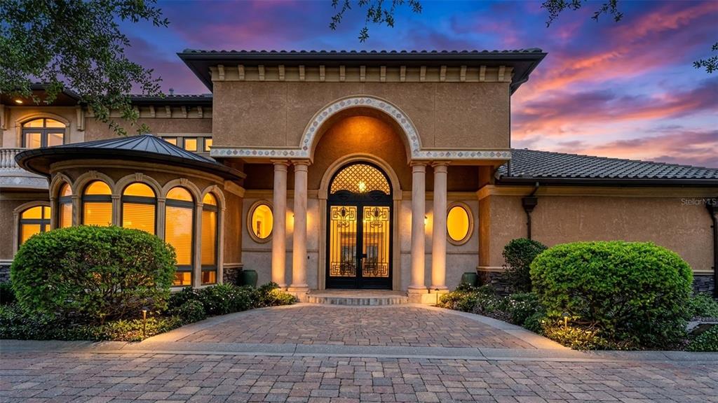A tan stucco house features a stone-paved entryway with arched windows and a decorative door — 5503 DOWNING STREET, DOVER, FL