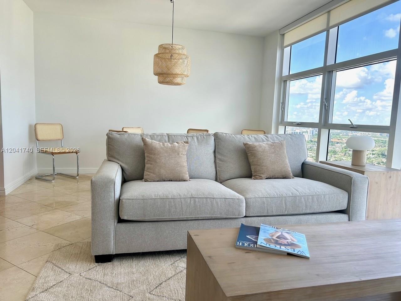 A living room features a light gray sofa, a wooden coffee table, and floor-to-ceiling windows — 1830 S Ocean Dr # 3707, Hallandale Beach FL 33009, HALLANDALE BEACH, FL