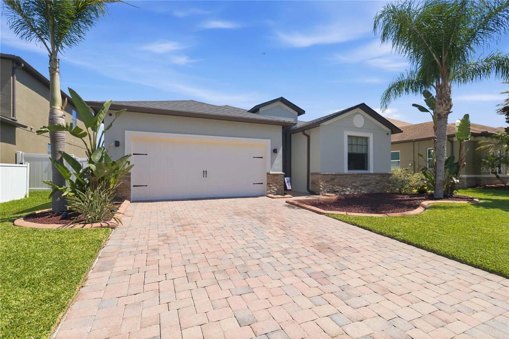 A single-story house with a paved driveway, a two-car garage, and palm trees — 4355 SUMMER BREEZE WAY, KISSIMMEE, FL