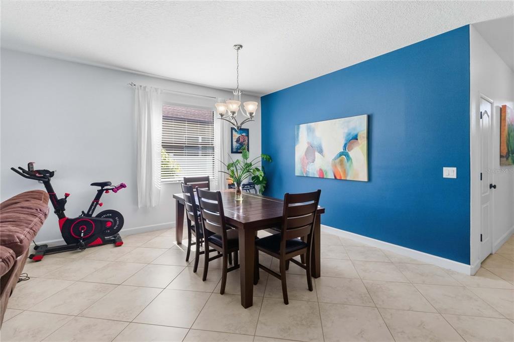 A dining room features a dark wood table, chairs, and a blue accent wall — 4355 SUMMER BREEZE WAY, KISSIMMEE, FL