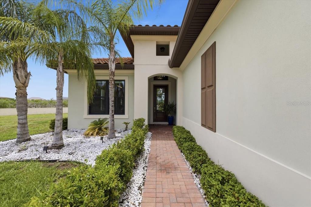 A brick walkway leads to the front entrance of a house with palm trees — 2317 5TH STREET E, PALMETTO, FL