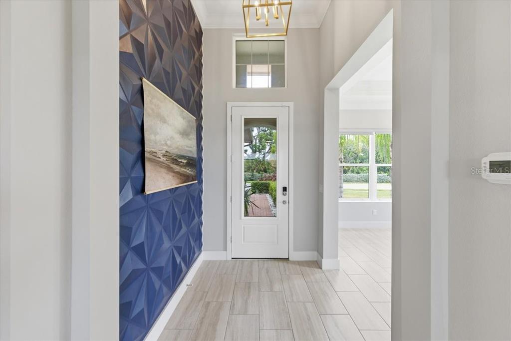 An entryway features a blue geometric accent wall, light wood-look tile flooring, and a door — 2317 5TH STREET E, PALMETTO, FL