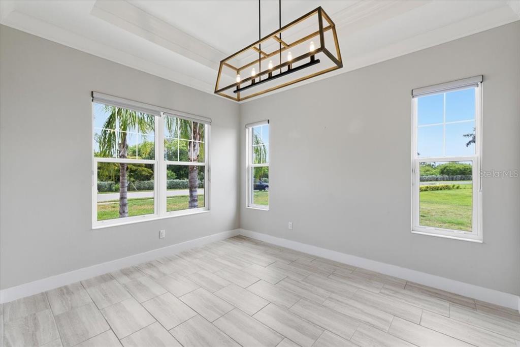 An empty dining room features light gray walls, wood-look tile flooring, and a rectangular chandelier — 2317 5TH STREET E, PALMETTO, FL