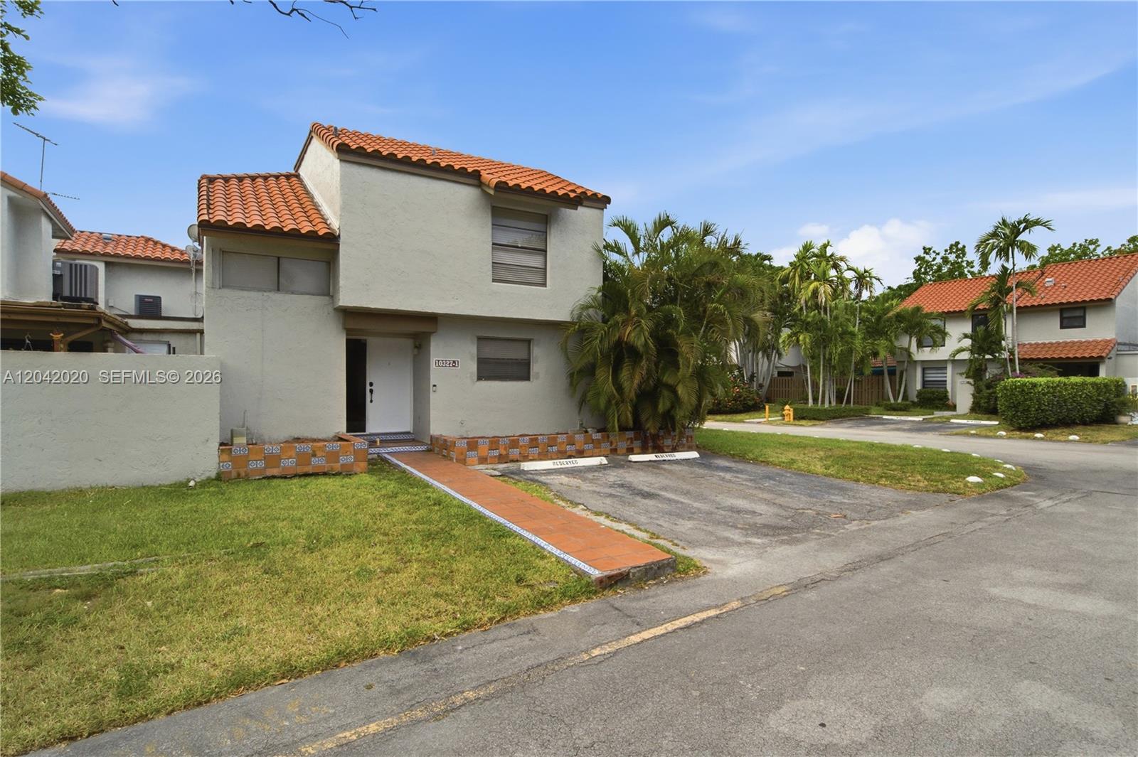 A two-story stucco townhouse features a red tile roof and a private parking space — 10327 NW 9th St Cir # 7, Miami FL 33172, MIAMI, FL