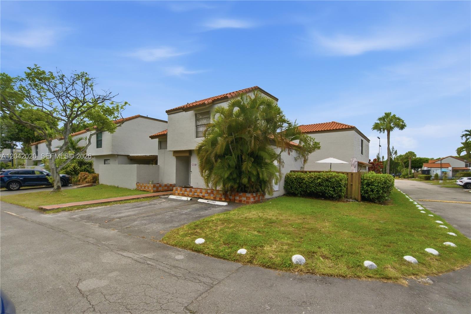 A two-story residential building with a tiled roof, a small front yard, and parking spaces — 10327 NW 9th St Cir # 7, Miami FL 33172, MIAMI, FL