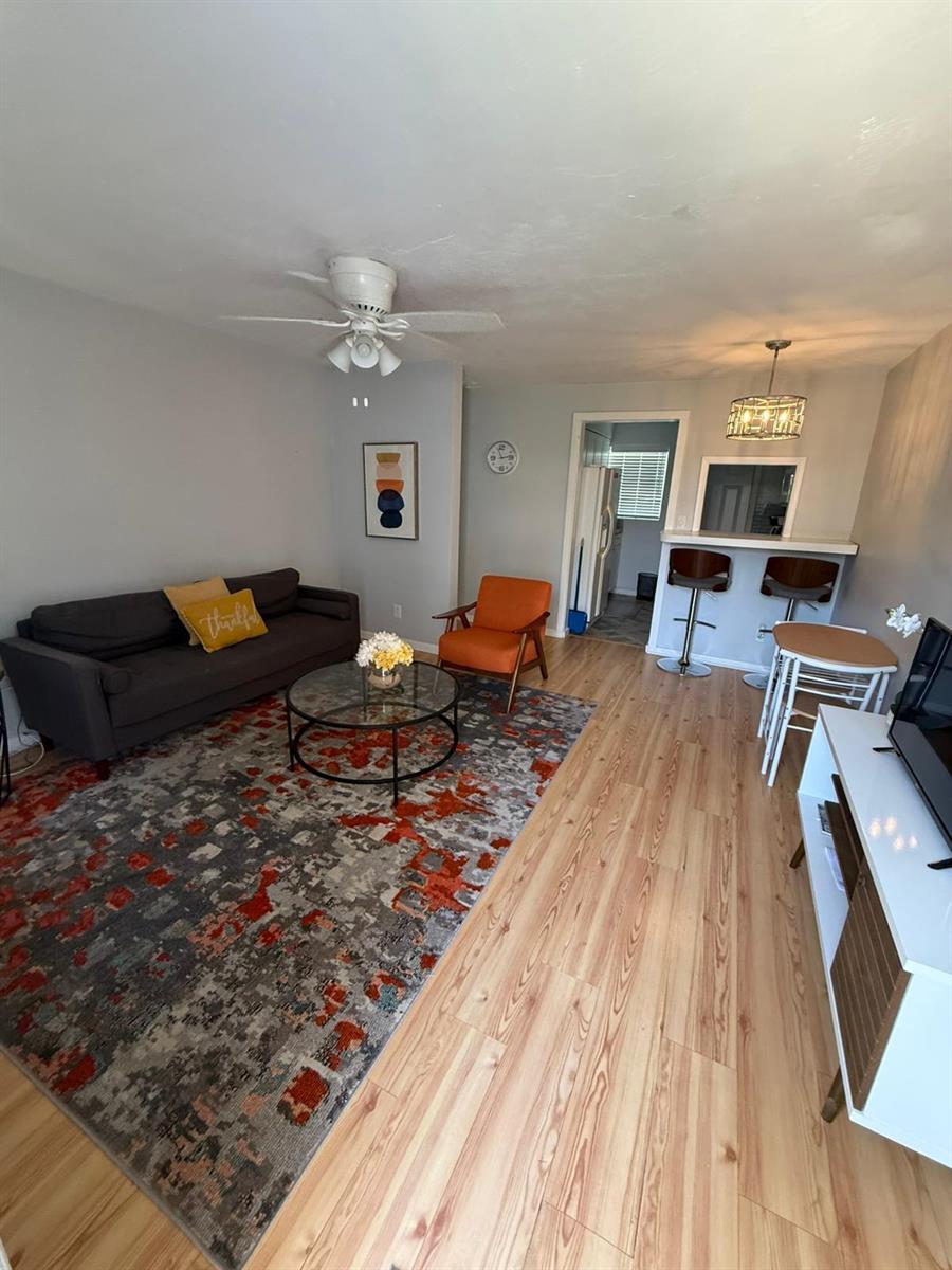 A living room features a grey sofa, orange armchair, patterned rug, and a breakfast bar — 27 NW 14th Avenue, Delray Beach FL 33444, DELRAY BEACH, FL