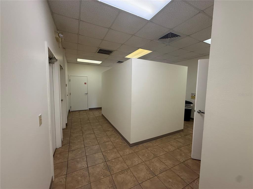 A hallway with tile flooring leads toward a white interior partition wall and closed doors — 2011 SW 20TH PLACE UNIT 103, OCALA, FL