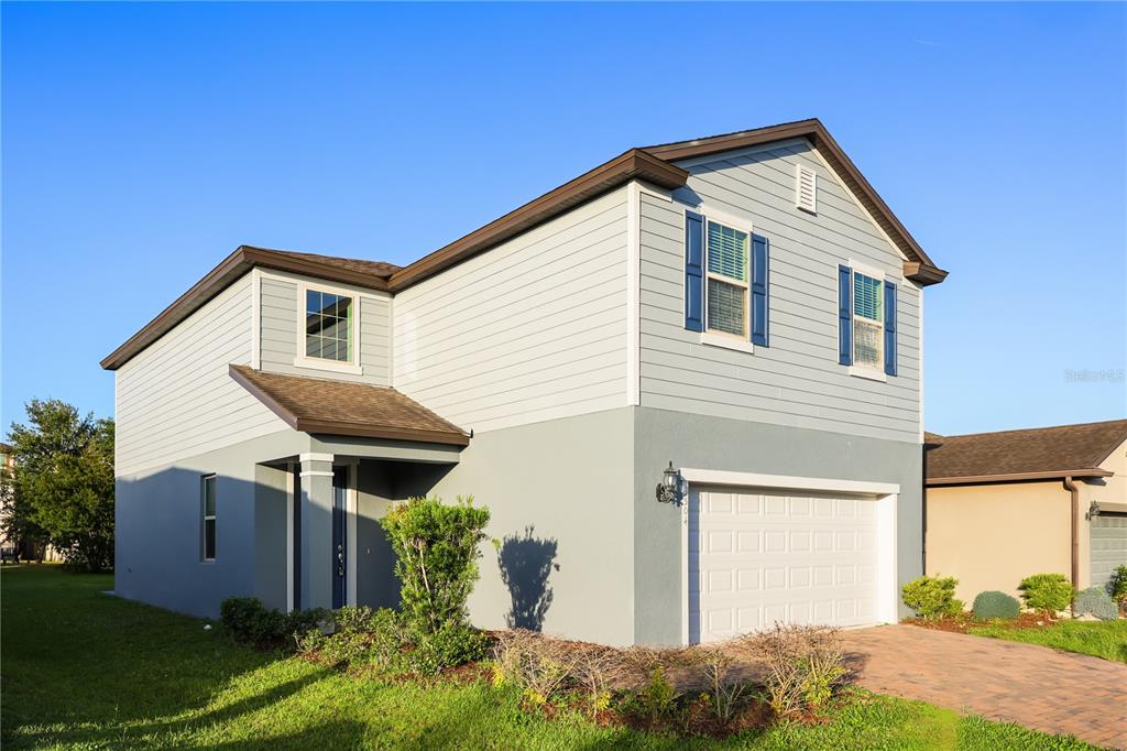 A two-story house with light-colored siding, a garage, and a paved driveway — 3504 SOUTHERN CROSS LOOP, KISSIMMEE, FL