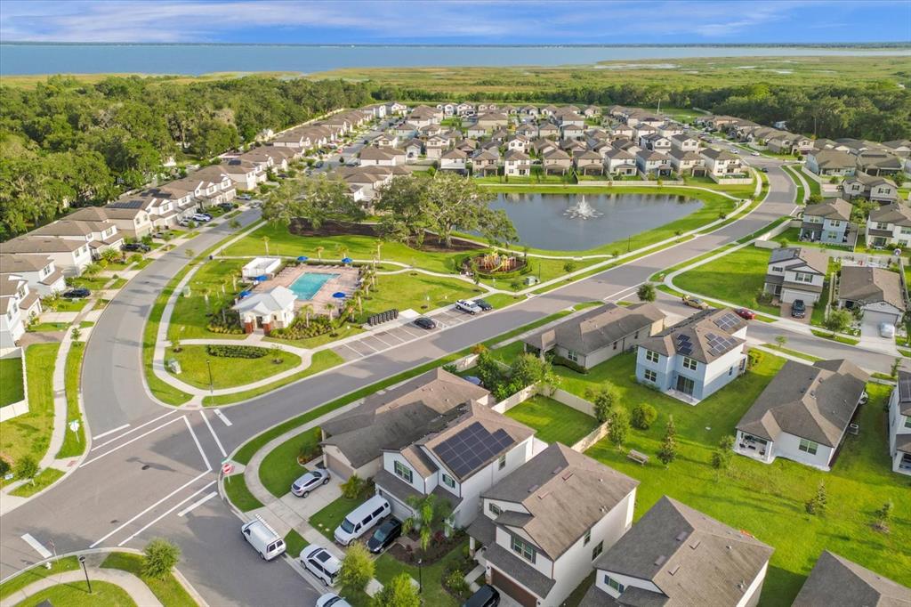 An aerial view shows a suburban neighborhood with a central pond, pool, and houses — 3504 SOUTHERN CROSS LOOP, KISSIMMEE, FL