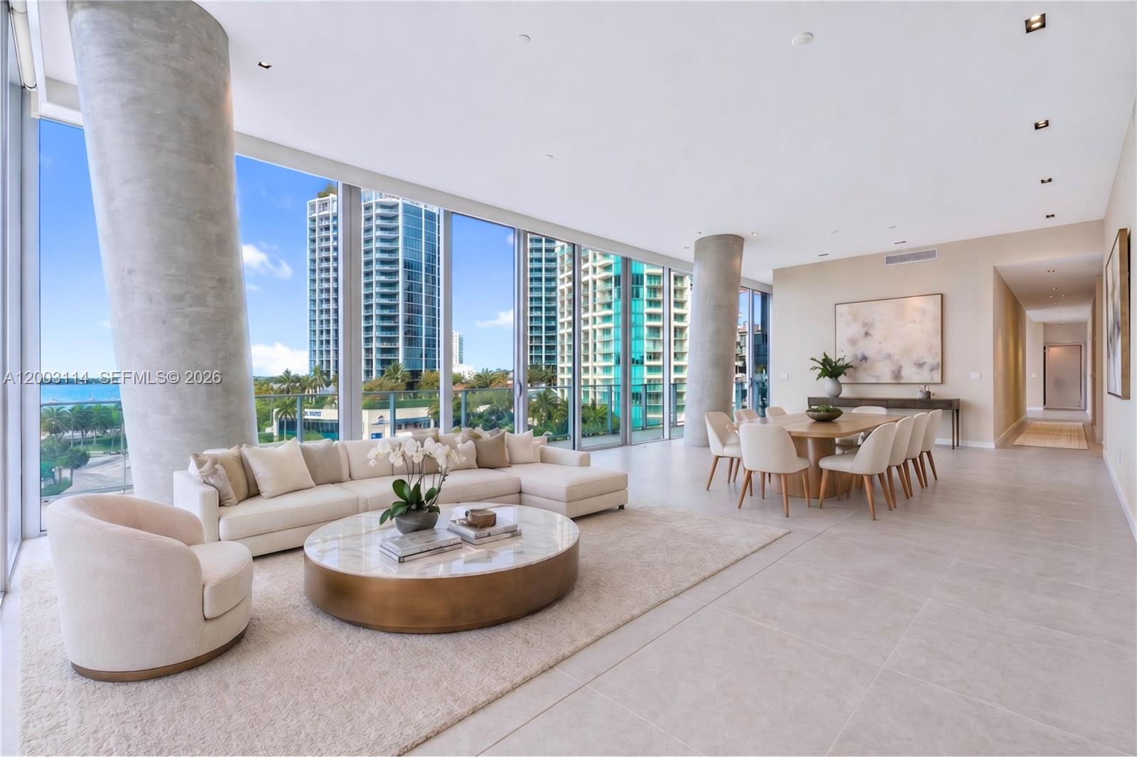 A spacious living and dining area features floor-to-ceiling windows, concrete columns, and neutral furnishings — 2675 S Bayshore Dr # 602S, Miami FL 33133, MIAMI, FL