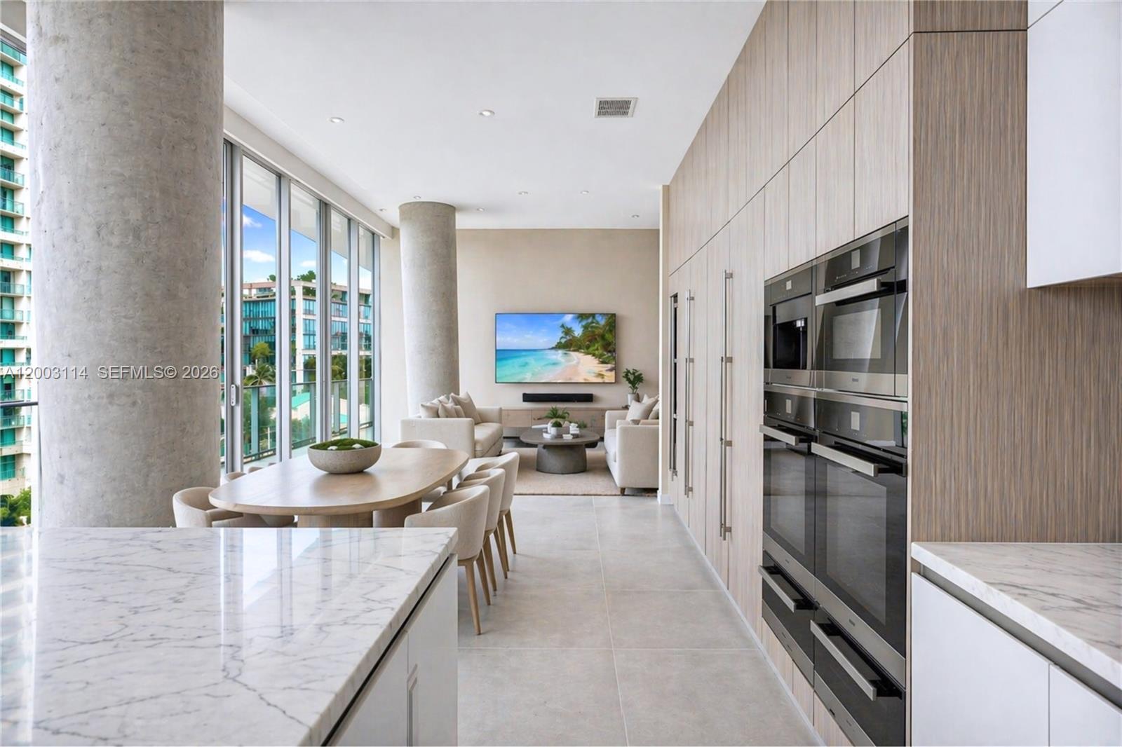 A modern open-plan kitchen and living area features light wood cabinetry, marble countertops, and floor-to-ceiling windows — 2675 S Bayshore Dr # 602S, Miami FL 33133, MIAMI, FL