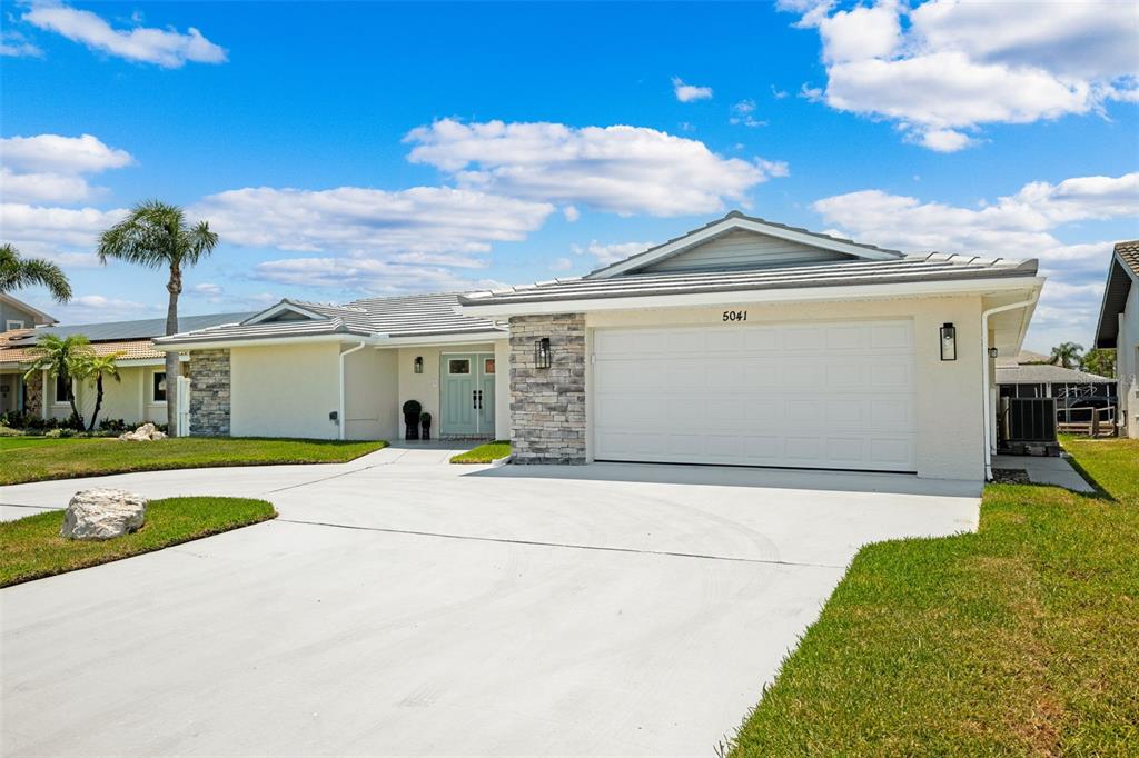 A light-colored house exterior features a teal double front door and a concrete walkway — 5041 CABRILLA COURT, NEW PORT RICHEY, FL
