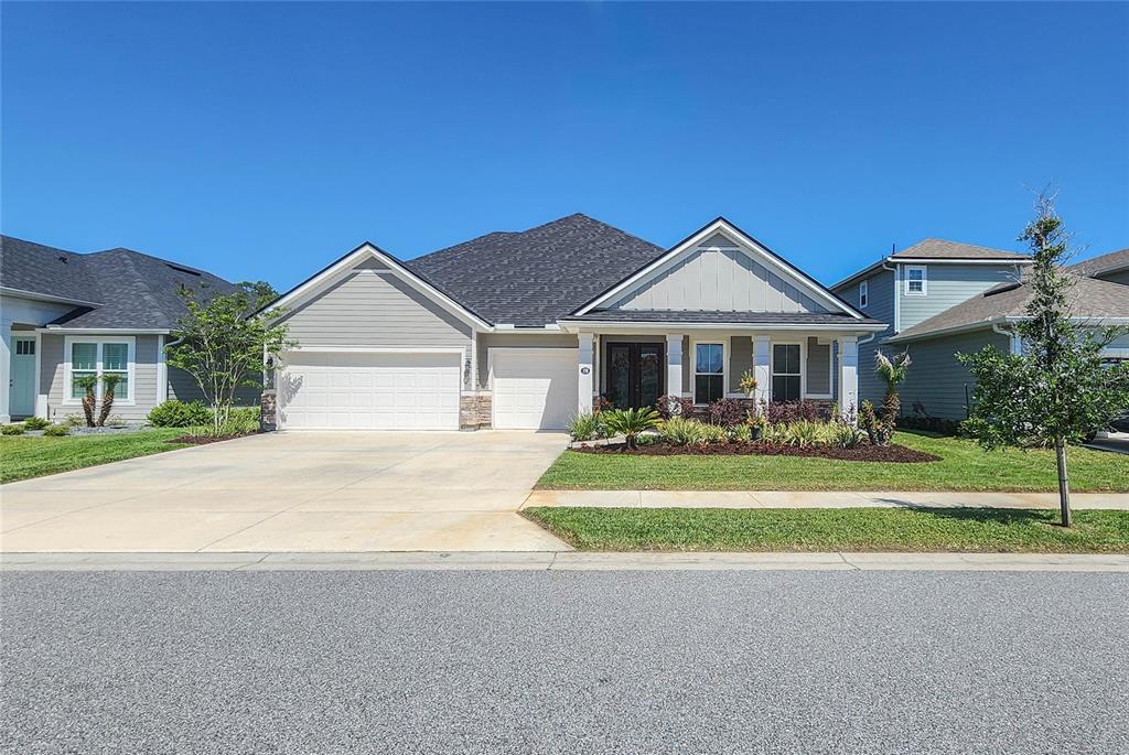 A single-story suburban house with a three-car garage, gray siding, and a covered front porch — 158 WOOD STORK LANE, PALM COAST, FL