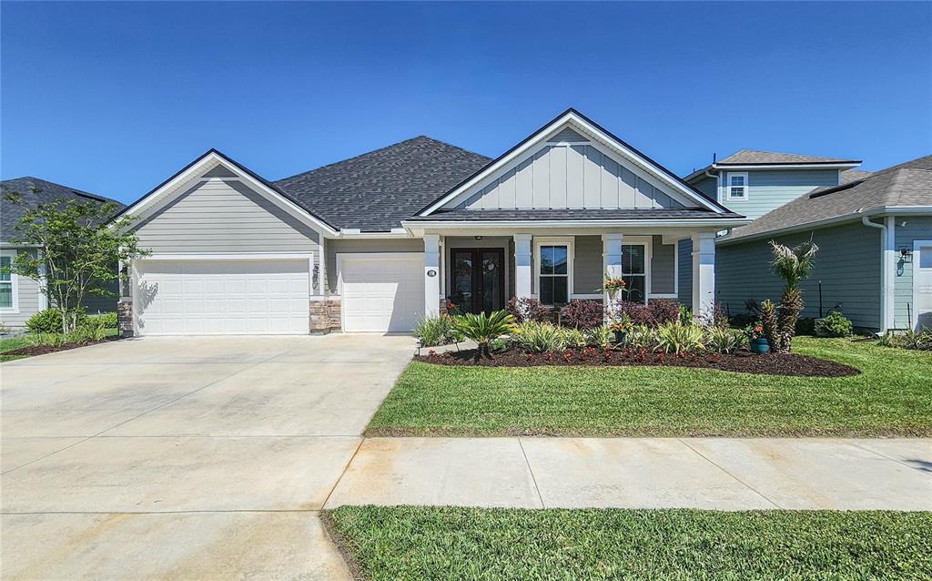 A single-story house with a gray exterior, a three-car garage, and a landscaped front yard — 158 WOOD STORK LANE, PALM COAST, FL
