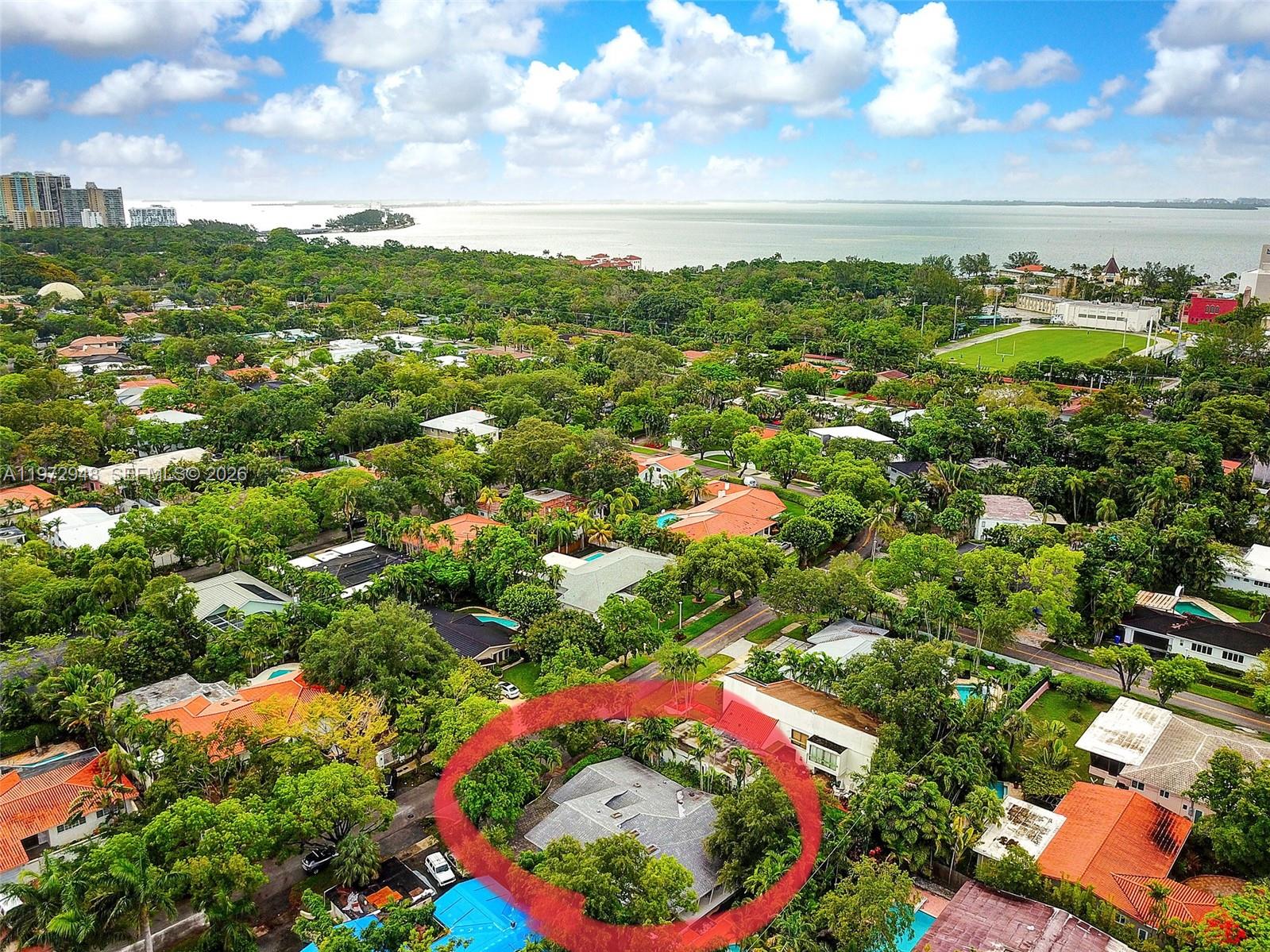 An aerial view shows a residential house with a gray roof surrounded by lush trees — 84 Bay Heights Dr, Miami FL 33133, MIAMI, FL