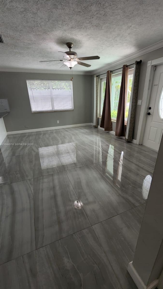 A room with gray walls, large glossy gray tile flooring, and a ceiling fan — LAKE WORTH, FL