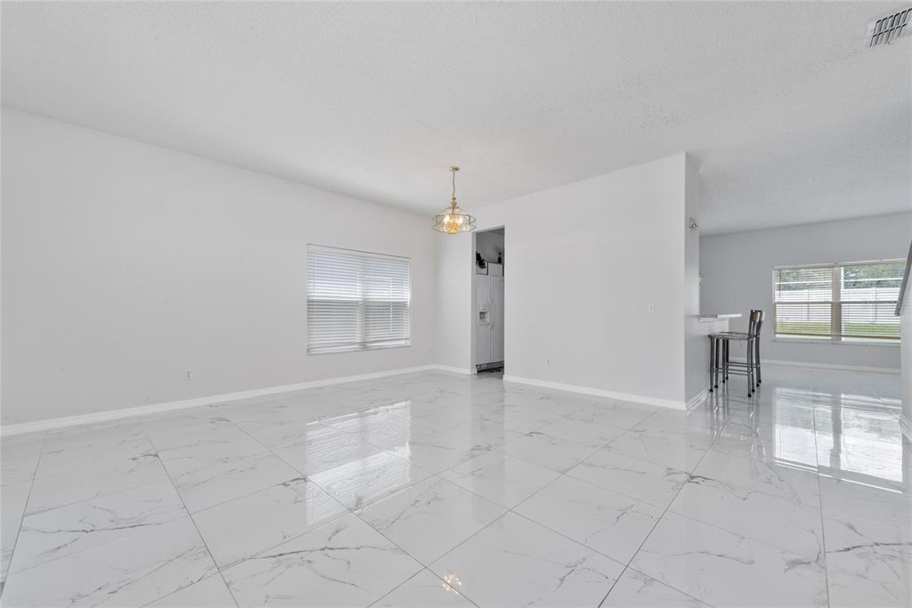 An open-concept dining area features white marble-look tile flooring and a modern pendant light — 746 LOCKBREEZE DRIVE, DAVENPORT, FL