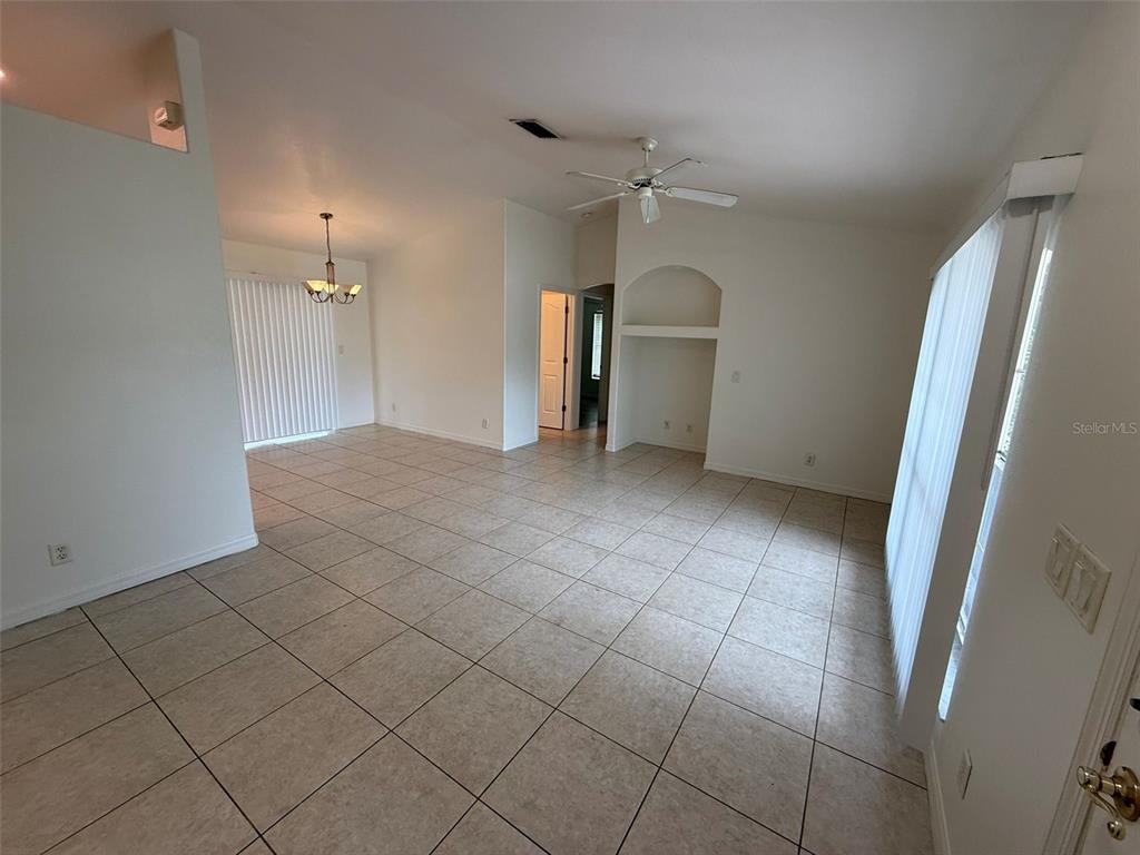 A tiled living area features a ceiling fan, an arched wall niche, and sliding glass doors — 3305 CIRCLEVILLE STREET, NORTH PORT, FL