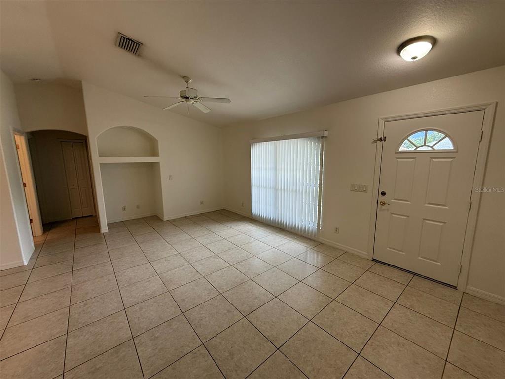 A living room with light-colored tile flooring, a ceiling fan, and a front entry door — 3305 CIRCLEVILLE STREET, NORTH PORT, FL