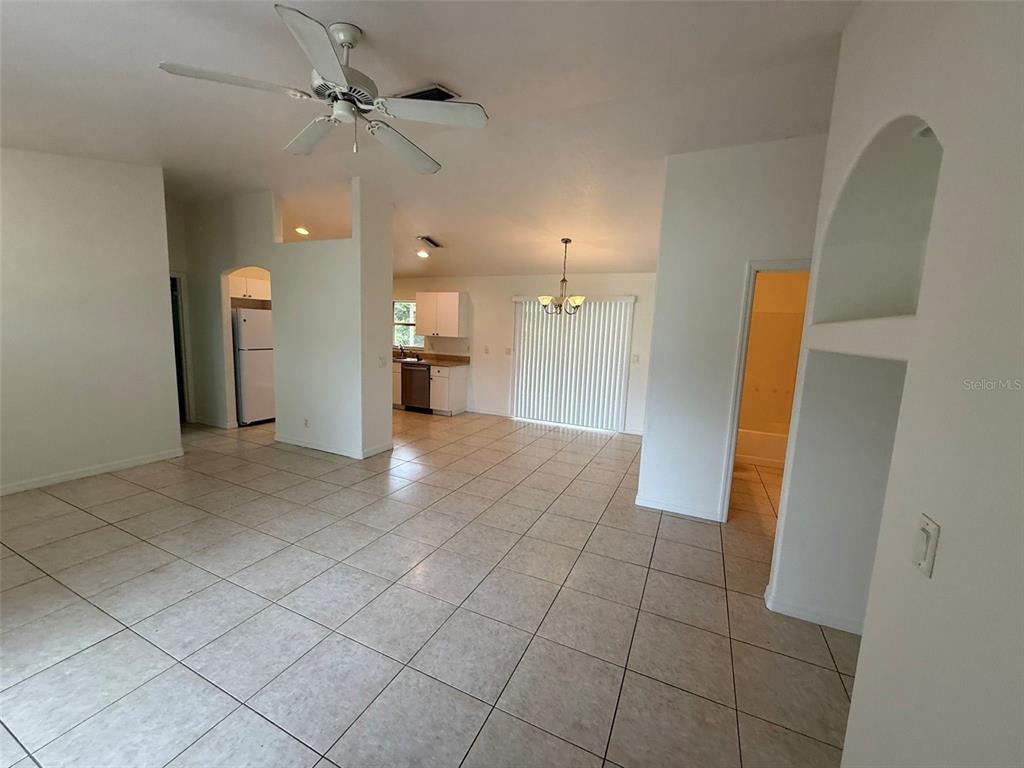 An open-concept living and dining area features white tile flooring, a ceiling fan, and kitchen — 3305 CIRCLEVILLE STREET, NORTH PORT, FL