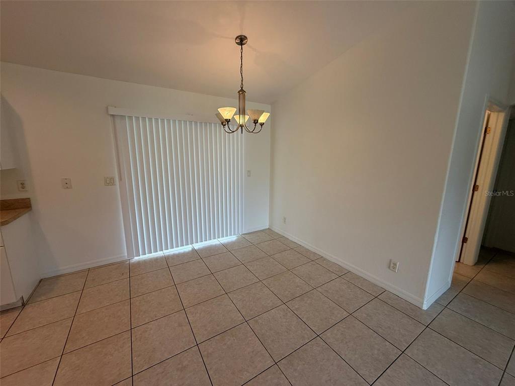 A dining area features beige tile flooring, a chandelier, and sliding glass doors — 3305 CIRCLEVILLE STREET, NORTH PORT, FL