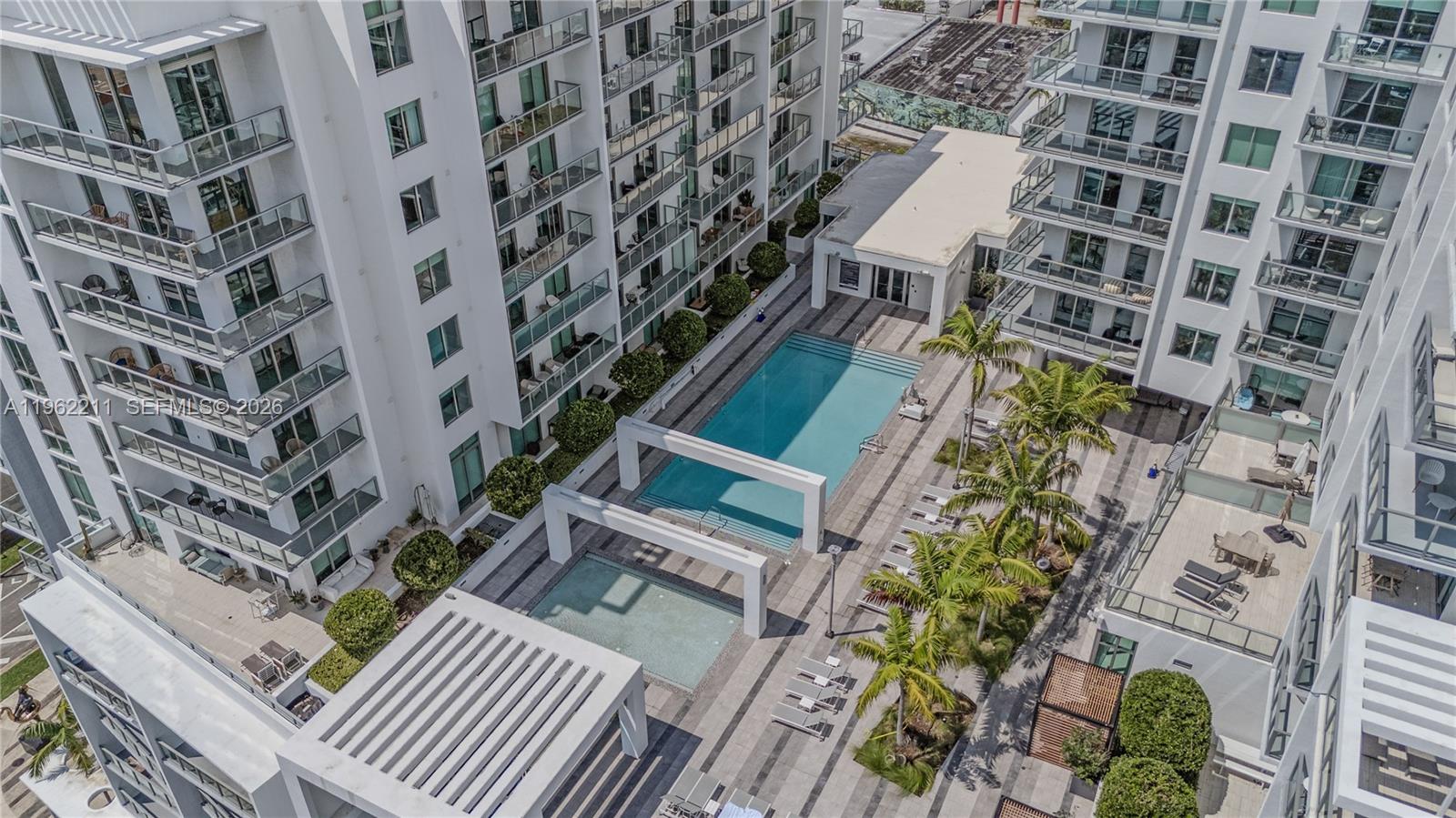 An aerial view shows a swimming pool and patio area surrounded by modern apartment buildings — 3900 Biscayne Blvd # 904, Miami FL 33137, MIAMI, FL