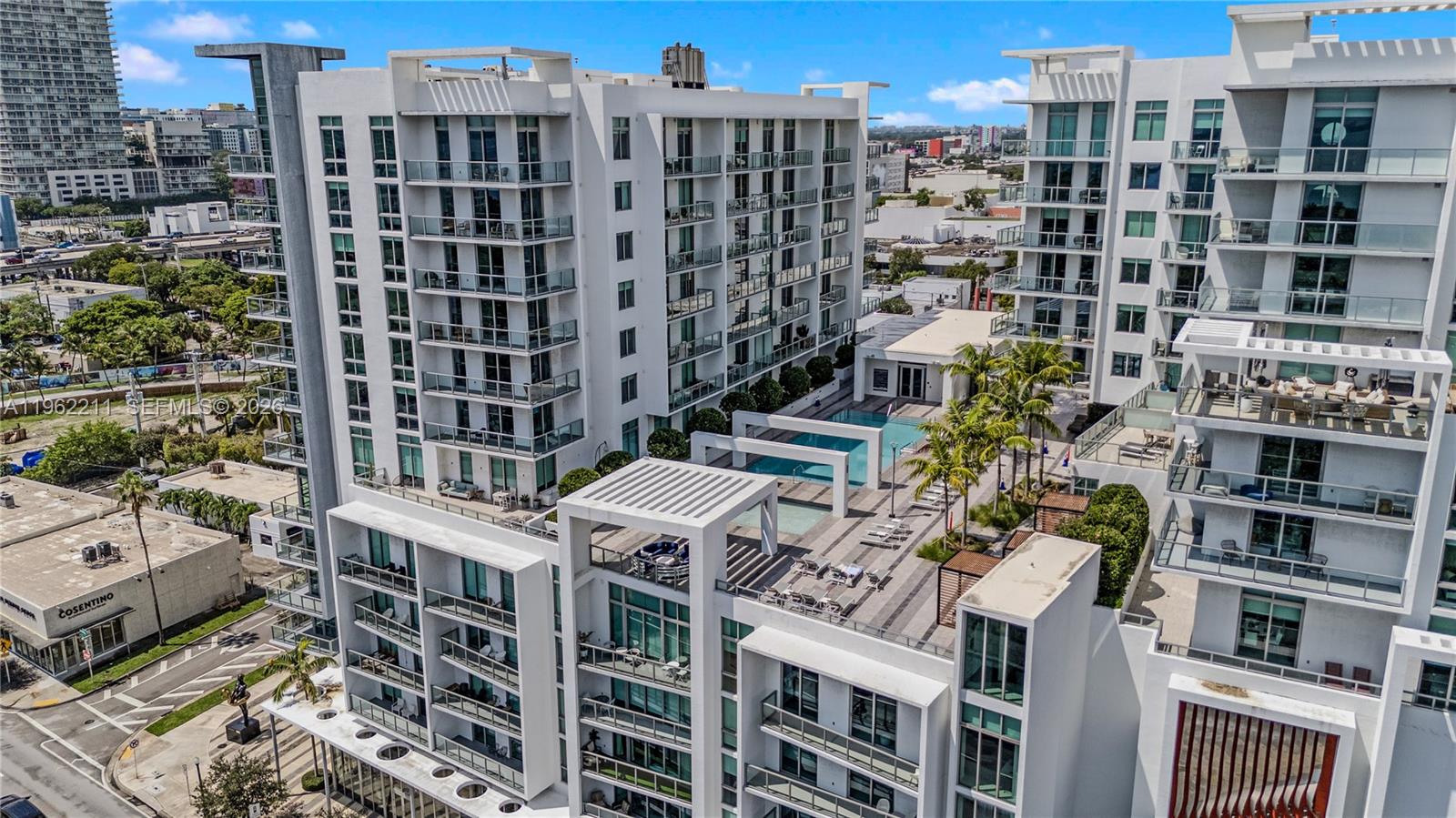 An aerial view shows a modern white apartment complex with a rooftop pool and deck — 3900 Biscayne Blvd # 904, Miami FL 33137, MIAMI, FL