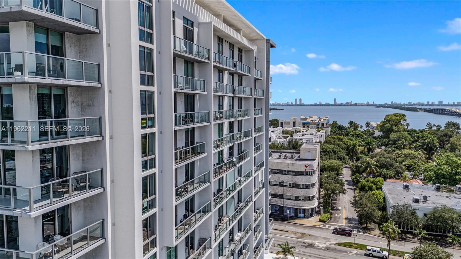 An exterior view of a modern high-rise apartment building overlooking a bay and city skyline — 3900 Biscayne Blvd # 904, Miami FL 33137, MIAMI, FL