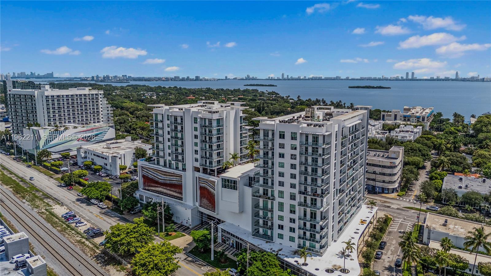 An aerial view shows two modern white apartment buildings situated near a large body of water — 3900 Biscayne Blvd # 904, Miami FL 33137, MIAMI, FL