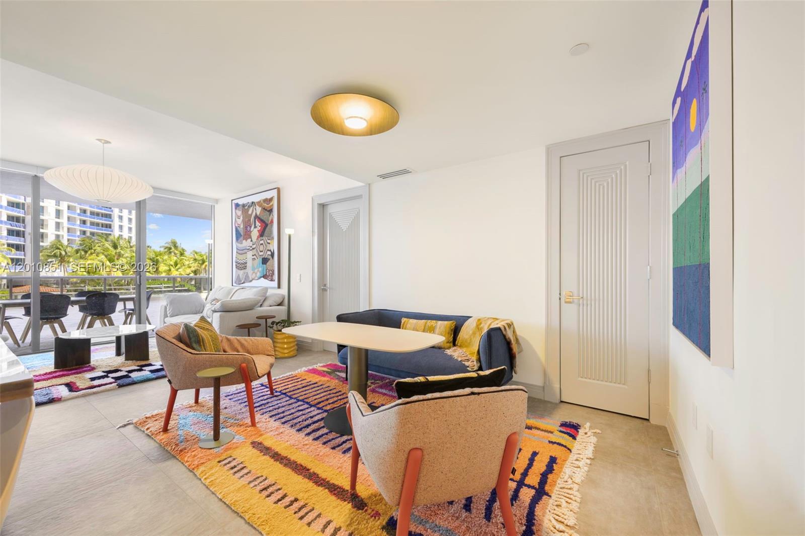 A living room features a colorful rug, a blue sofa, two armchairs, and a balcony — 5875 Collins Ave # 503, Miami Beach FL 33140, MIAMI BEACH, FL