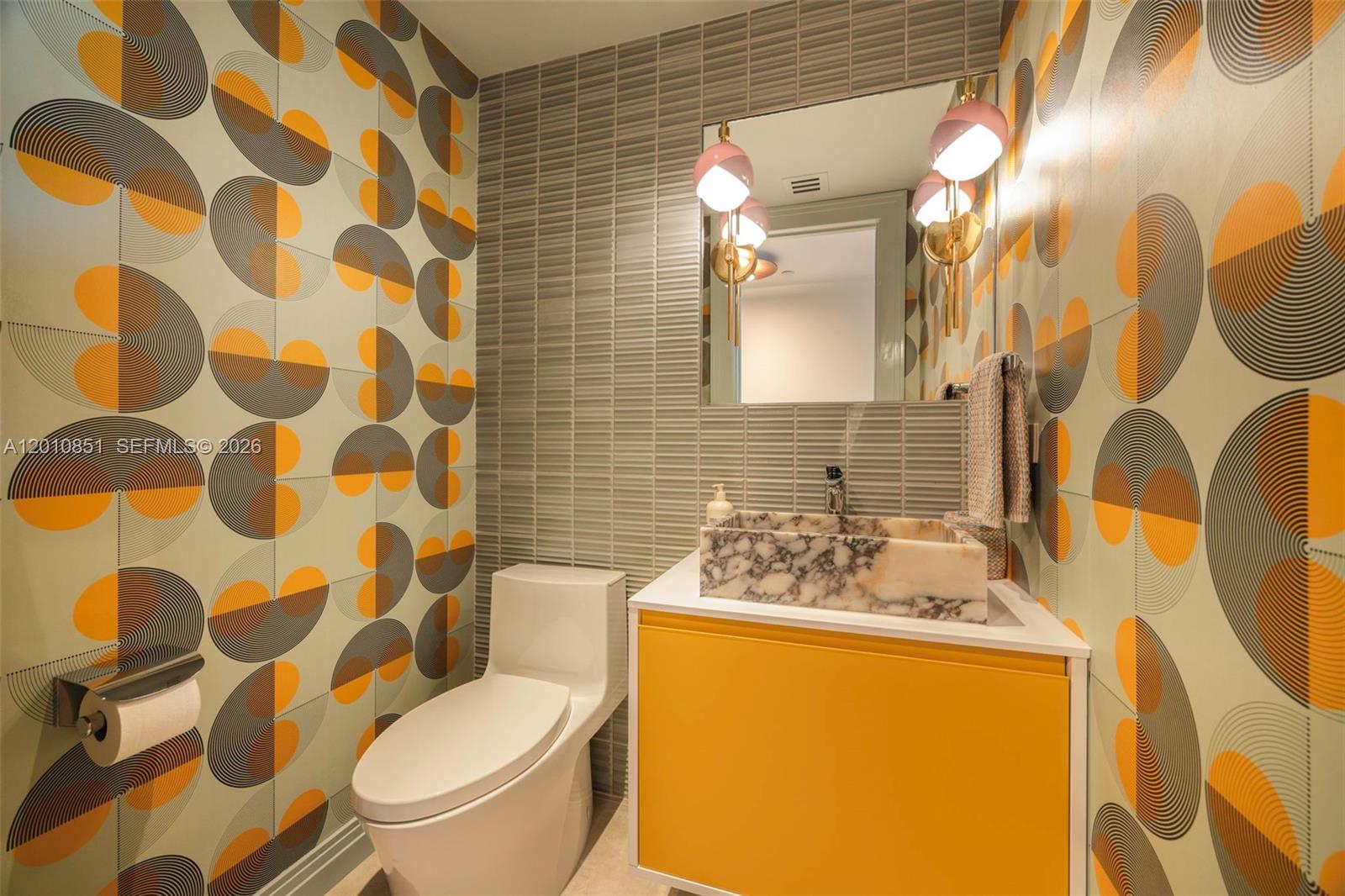 A powder room features patterned wallpaper, a marble vessel sink, and a yellow vanity cabinet — 5875 Collins Ave # 503, Miami Beach FL 33140, MIAMI BEACH, FL