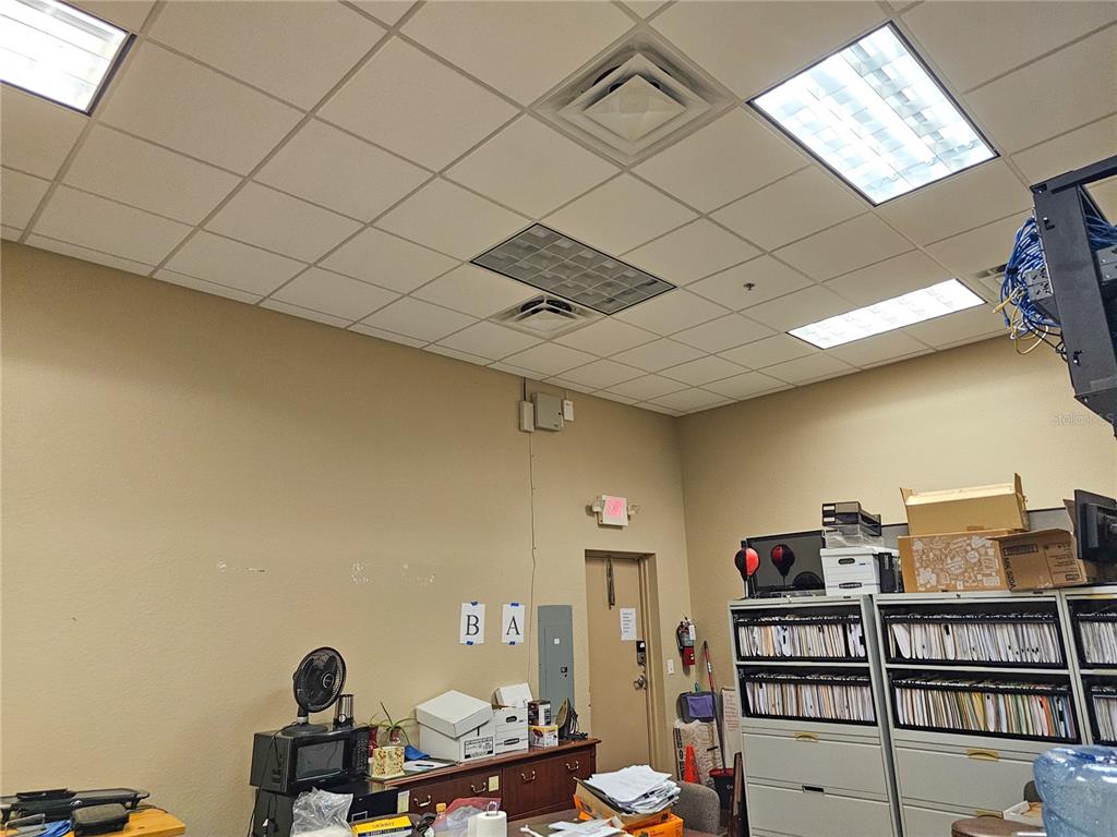 This office space features a drop ceiling, beige walls, and storage cabinets filled with files — 422 S ALAFAYA TRAIL UNIT 30, ORLANDO, FL