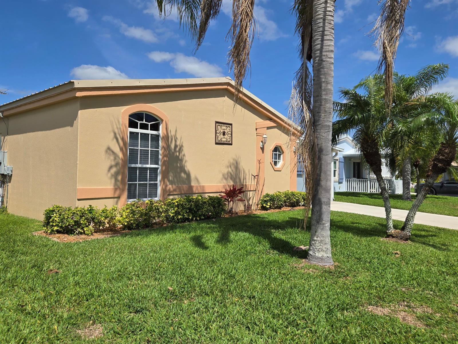 A tan, single-story house with a large arched window and a palm tree in front — 4311 SW 9th Way, Okeechobee FL 34974, OKEECHOBEE, FL