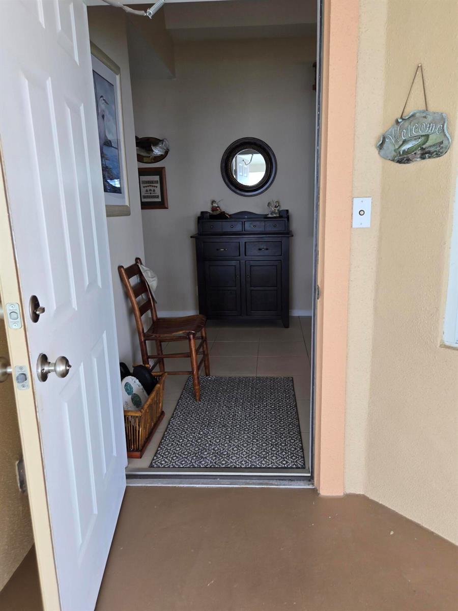 An entryway features a wooden chair, a dark cabinet, a round mirror, and a rug — 4311 SW 9th Way, Okeechobee FL 34974, OKEECHOBEE, FL