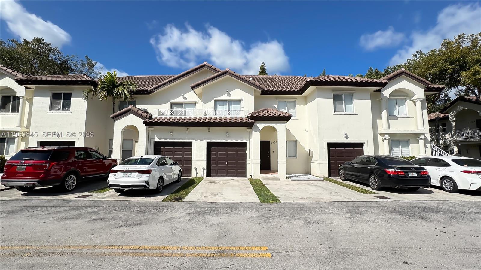 A row of two-story townhomes with brown garage doors and beige stucco exteriors — 8902 NW 109th Ct # 1203, Doral FL 33178, DORAL, FL