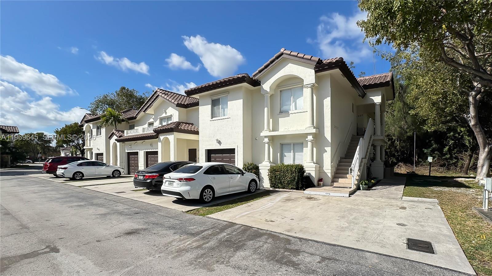 A row of two-story townhouses with stucco exteriors, tile roofs, and attached garages — 8902 NW 109th Ct # 1203, Doral FL 33178, DORAL, FL